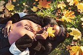 Young adult black woman lying down in yellow autumn leaves
