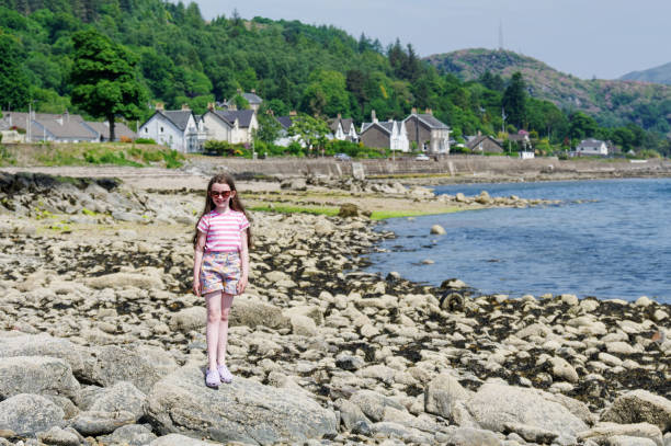 Happy young girl on the beach at Tighnabruaich in Argyll and Bute on the west coast of Scotland during the summer Happy young girl on the beach at Tighnabruaich in Argyll and Bute on the west coast of Scotland during the summer UK loch fyne stock pictures, royalty-free photos & images