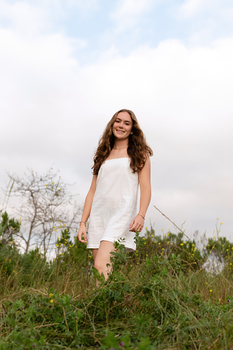 Teenage girl wearing a white dress in pasture