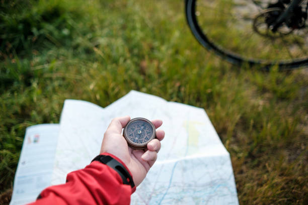 неузнаваемый велосипедист, использующий компас поверх карты. - journey footpath exercising effort стоковые фото и изображения