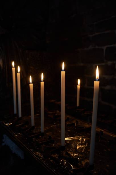 Dramatic image of numerous flickering candles illuminating a shadowy church interior