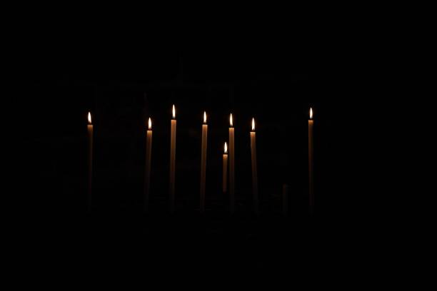 Dramatic image of numerous flickering candles illuminating a shadowy church interior