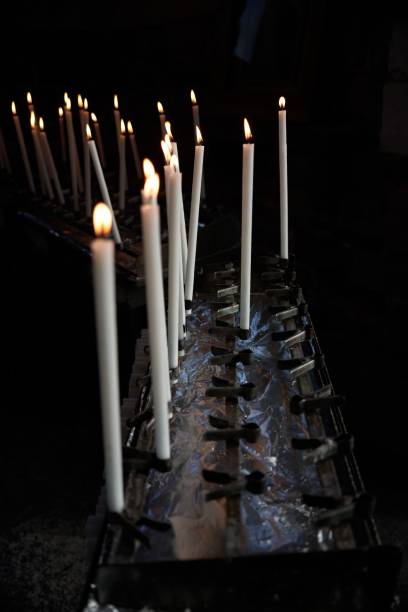 Dramatic image of numerous flickering candles illuminating a shadowy church interior