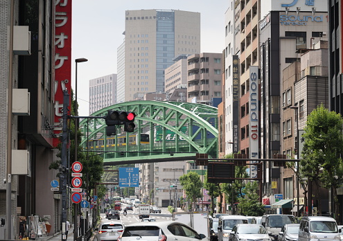 May 22, 2023 - Chiyoda City, Japan: The green elevated railway bridge known as Shoheibashi carries the yellow Chuo-Sobu Line over the Kanda River. Spring afternoon in Akihabara Electric Town.