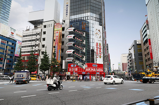 May 22, 2023 - Chiyoda City, Japan: Traffic flows near the colorful commercial signs at the intersection of 1 Chome -Sotokanda and Akihabara Station Minari-dori Street. Spring afternoon.