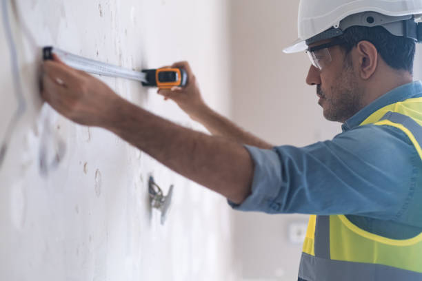 istock Focused engineer using tape-line to measure distance on wall for socket hole 1498224458