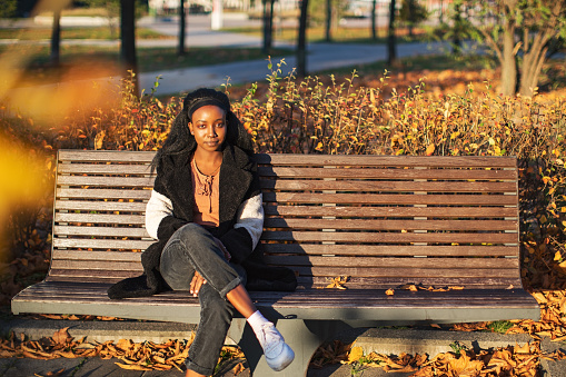 Young adult black woman siting on park bench
