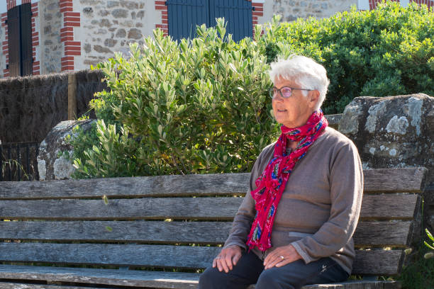 Portrait of an 80-year-old lady enjoying a public park. Wearing white blouse and red scarf.