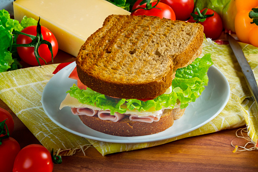 Sandwich with Ham, cheese, lettuce, integral bread, and tomatoes on a table with ingredients