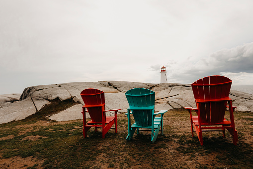 Wooden chairs facing the lighthouse at Peggy's Cove  along the coast of Nova Scotia, Canada. Shot with a Canon 5D Mark IV.