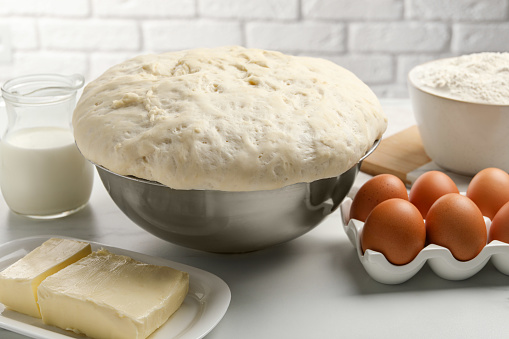 Fresh yeast dough, eggs and ingredients on white table. Making cake