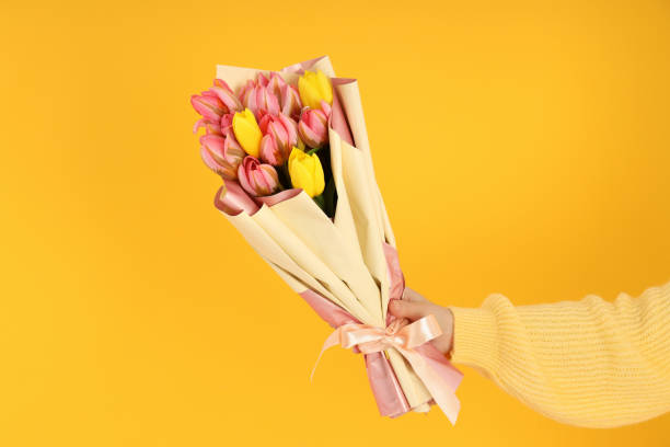 istock Woman's hand holding a bouquet on a yellow background 1498239764
