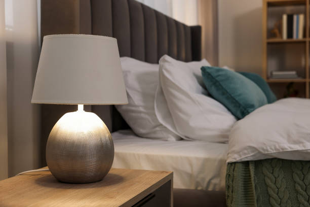 istock Lamp on wooden bedside table and comfortable gray bed in bedroom 1498240020