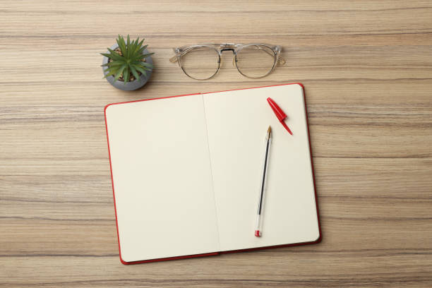 istock Ballpoint pen, notebook and glasses on wooden table, flat lay 1498240166
