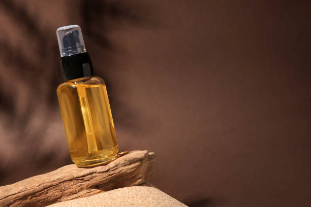istock Bottle of serum and tree bark on sand against brown background. Space for text 1498240227