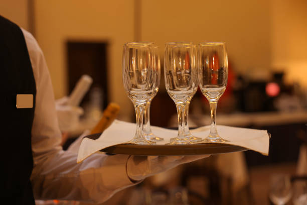 Butler holding tray with empty glasses in restaurant, closeup