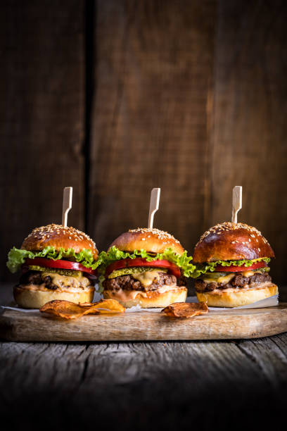 istock Tasty cheeseburger with lettuce, cheddar cheese, tomato and pickles. Burger bun with sesame seeds. Rustic atmosphere. Delicious fast food meal. 1498243675