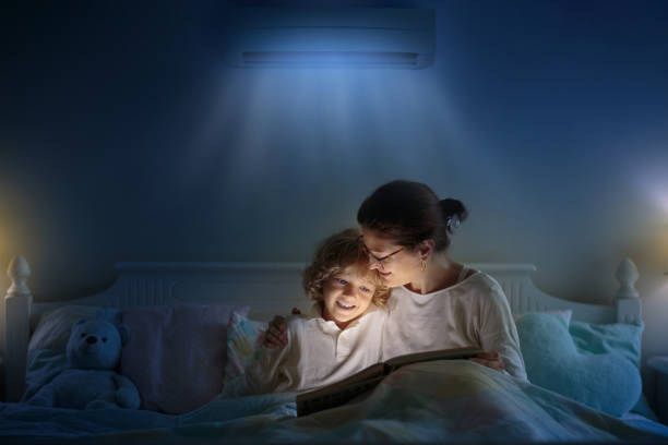 Air conditioner in bedroom. Kids room climate Air conditioner in bedroom. Kids room climate control. Mother and child in bed under cool air breeze. Comfortable temperature for healthy sleep on summer night. Air conditioning device in family home. air conditioner family stock pictures, royalty-free photos & images