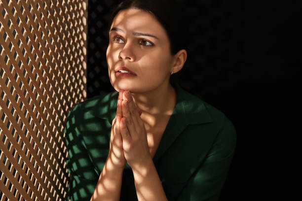ブースでの告白中に神に祈る女性 - confession booth ストックフォトと画像