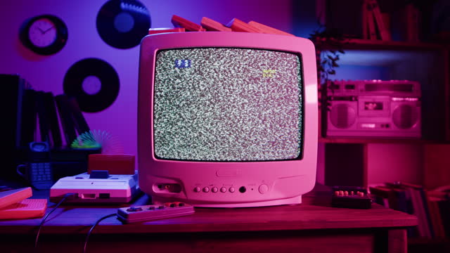Old television with grey interference screen in retro room. Close-up of vintage tv and cartridges for playstation. Antique video game, nostalgia.