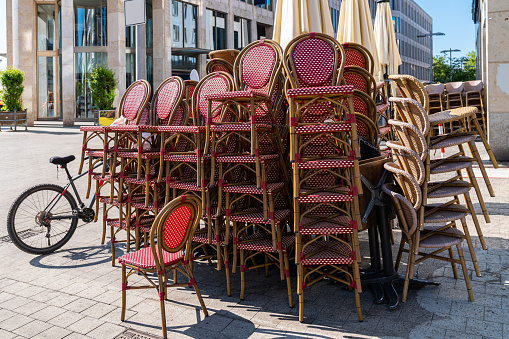 Wicker chairs of a street cafe stacked in a pedestrian zone.