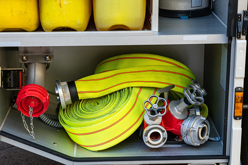 Yellow fire hose rolled up and a water splitter with valves in a fire track. Close-up.