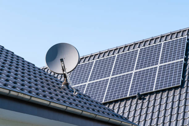 fragmento do telhado de um edifício residencial com painéis solares instalados e uma antena parabólica. - solar power station audio - fotografias e filmes do acervo