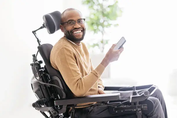 Photo of Disabled Black Man Using Smartphone at Home