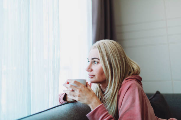 istock Pensive mature woman drinking tea and looking through window 1498252558