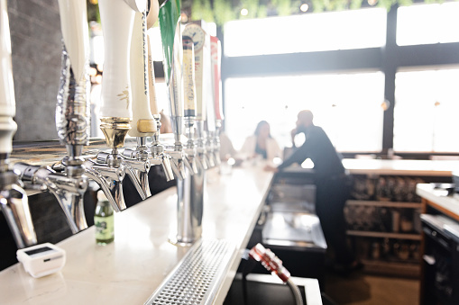 Bar counter with beer spouts with a client and bartender at the back