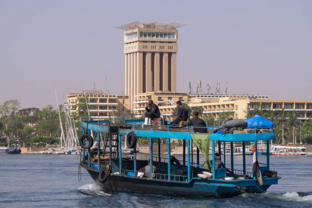 Aswan, Egypt - April 28, 2023: Boat for the transport of workers navigating the Nile river in front of the hotel zones of the city