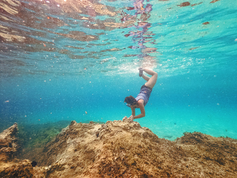 Underwater shoot of a teenage girl snorkeling in crystal blue sea on a Greek island
