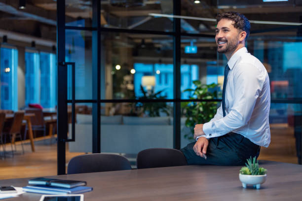 Portrait of a business man sitting on a board room table. stock photo