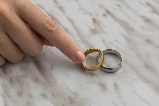 person hand taking engagement rings in studio, beautiful jewelry with marble texture in the background, love and celebration with marriage, symbol and luxurious objects
