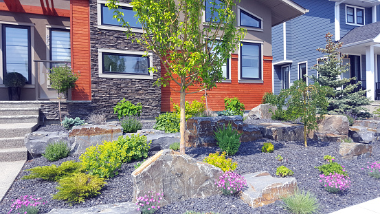 Calgary, Alberta, Canada- June 12,2023:  Two new modern homes with beautiful xeriscaped front yard. Small easy to look after plants and gorgeous rocks.  Variation of plants.