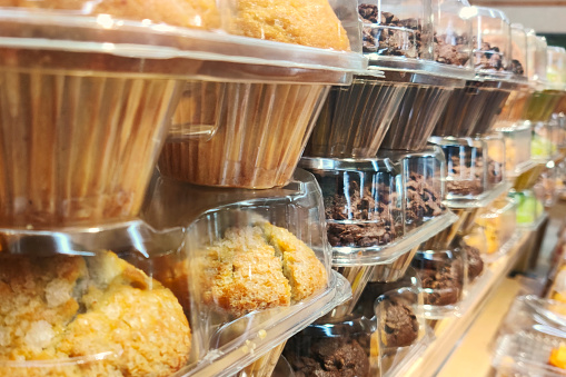 Muffins in grocery store, supermarket or bakery in plastic packaging background food photo. Assorted variety of different kinds of muffins.