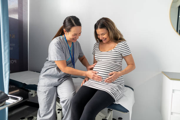 midwife check pregnant patients abdominal for fetal positioning - human pregnancy midwife healthcare and medicine visit imagens e fotografias de stock