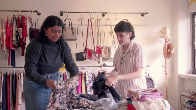 Multiracial Coworkers Sorting out Clothes on a Messy Table In Store