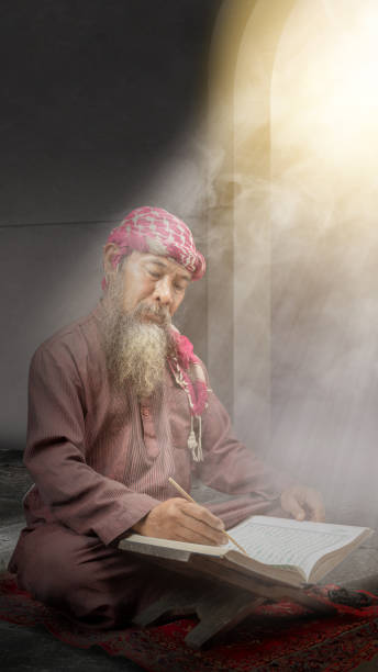 Muslim man with a beard wearing keffiyeh with agal sitting and reading the Quran Muslim man with a beard wearing keffiyeh with agal sitting and reading the Quran on the prayer rug inside the mosque middle eastern ethnicity mature adult book reading stock pictures, royalty-free photos & images