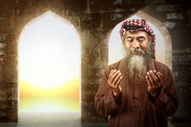 istock Muslim man with a beard wearing keffiyeh with agal in praying while raised hands 1498294716
