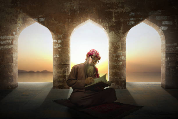 Muslim man with a beard wearing keffiyeh with agal sitting and reading the Quran on the prayer rug Muslim man with a beard wearing keffiyeh with agal sitting and reading the Quran on the prayer rug inside the mosque middle eastern ethnicity mature adult book reading stock pictures, royalty-free photos & images