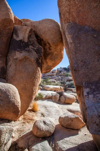 View of the desert landscape through a gap between two giant boulders in Joshua Tree National Park
