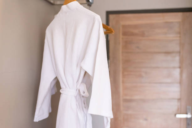 istock Fresh and clean white bathrobe hanging on rack in bathroom 1498299500
