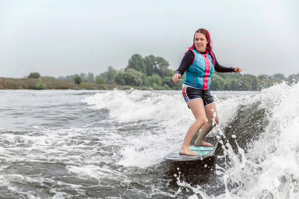 mujer joven despertando por las olas del río - wakeboarding motorboating extreme sports waterskiing fotografías e imágenes de stock