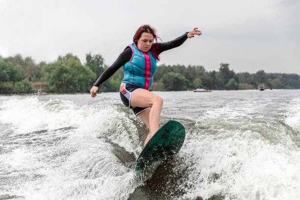 mujer joven despertando por las olas del río - wakeboarding motorboating extreme sports waterskiing fotografías e imágenes de stock