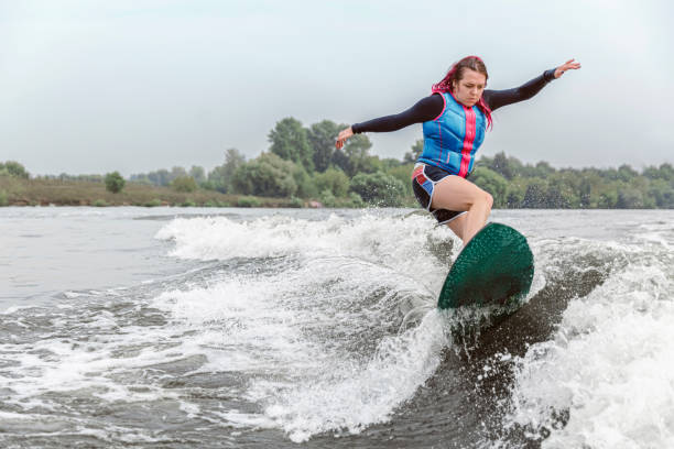 mulher nova que surfa pelas ondas do rio - wakeboarding motorboating extreme sports waterskiing - fotografias e filmes do acervo