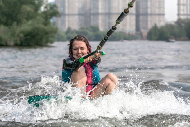 молодая женщина просыпается по волнам реки - wakeboarding motorboating extreme sports waterskiing стоковые фото и изображения