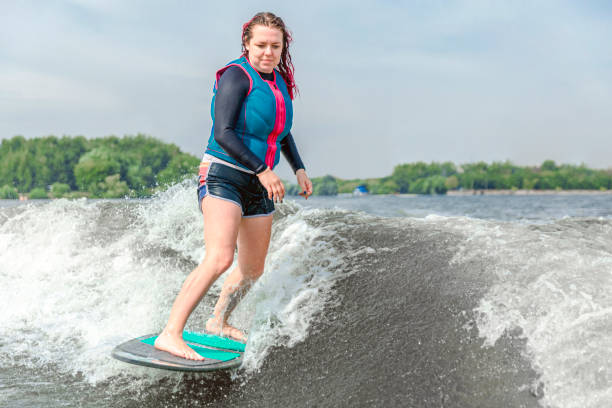 giovane donna che fa wakesurf lungo le onde del fiume - wakeboarding motorboating extreme sports waterskiing foto e immagini stock
