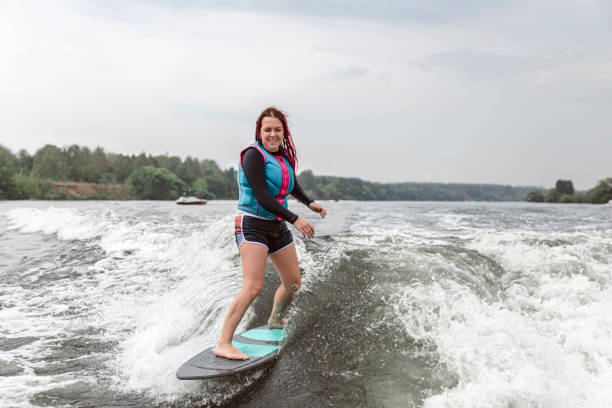 молодая женщина просыпается по волнам реки - wakeboarding motorboating extreme sports waterskiing стоковые фото и изображения