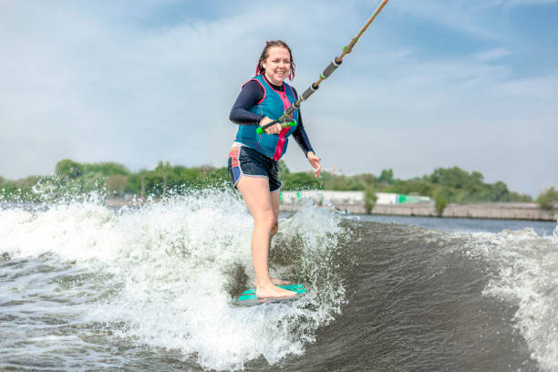 giovane donna che fa wakesurf lungo le onde del fiume - wakeboarding motorboating extreme sports waterskiing foto e immagini stock